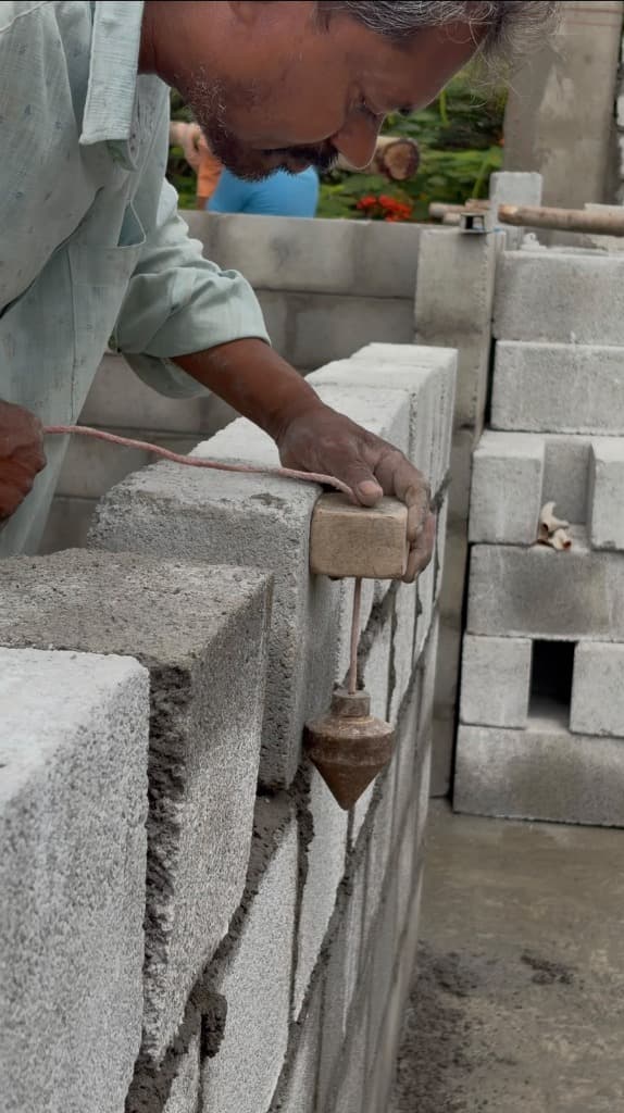 KSM Constructions — Mason checking plumb line accuracy